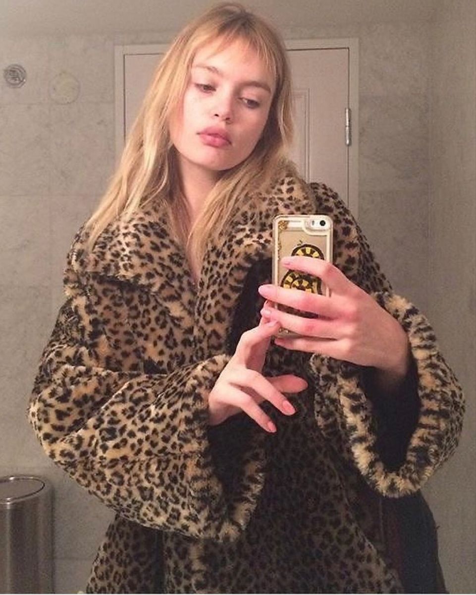 Woman wearing a leopard-print coat taking a mirror selfie
