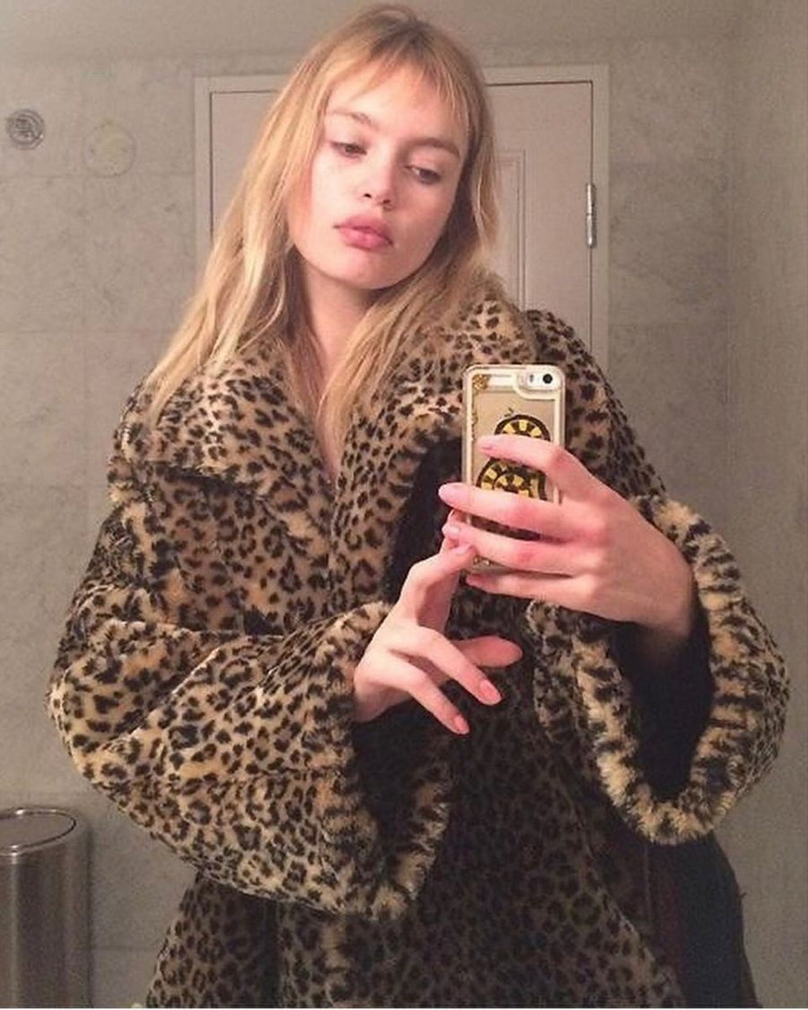 Woman wearing a leopard-print coat taking a mirror selfie