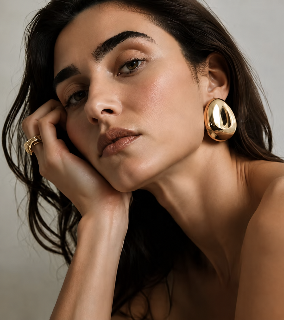 Rita wearing sculptural gold earrings